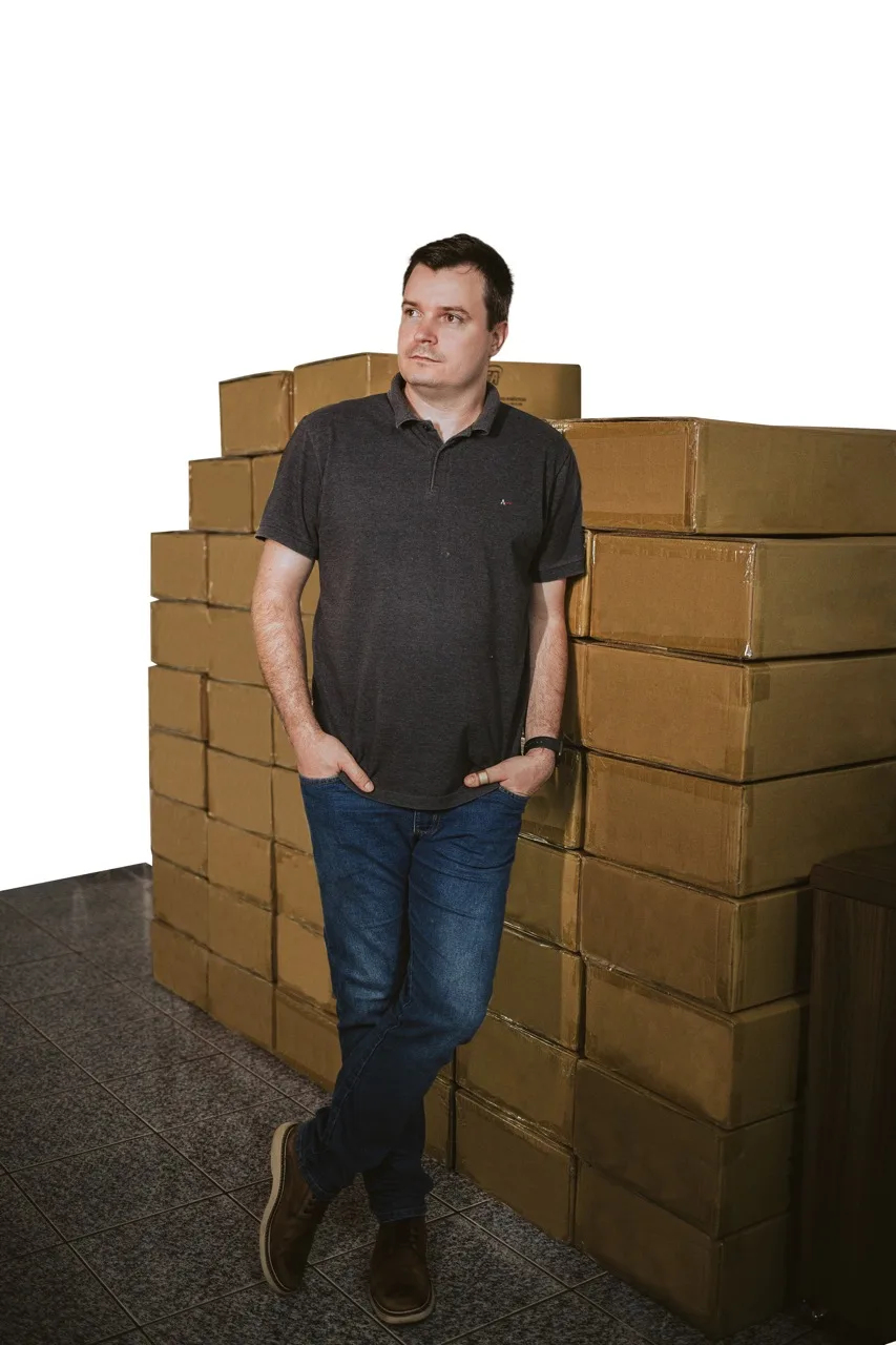 Guilherme Vasques ao lado de caixas de estoque