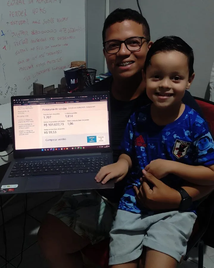 Aluno com o filho mostrando painel de vendas da Amazon com R$ 101 mil